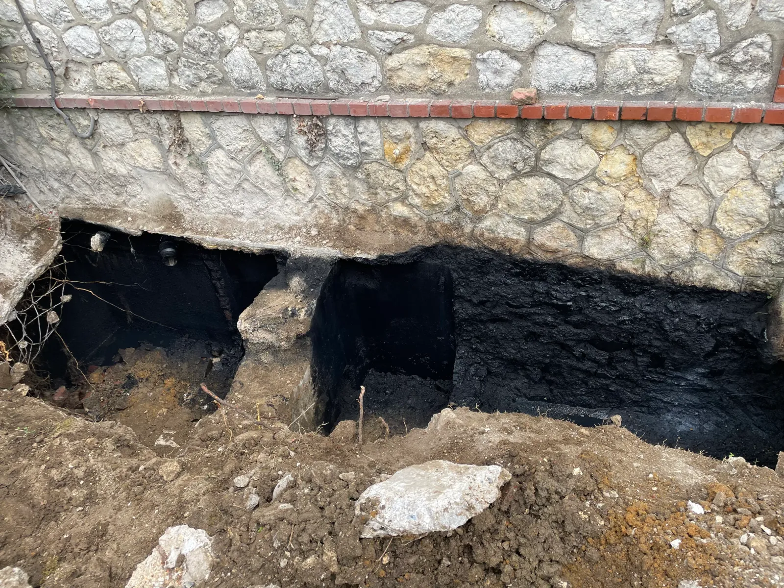 Ouverture d'une fouille le long d'un mur pour des travaux d'assainissement