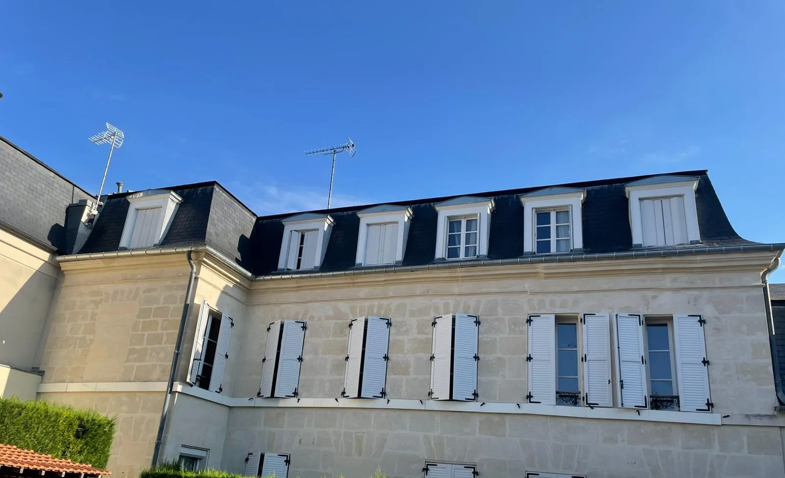 Grande demeure en pierre de taille à la façade ravalée, vue depuis la cour