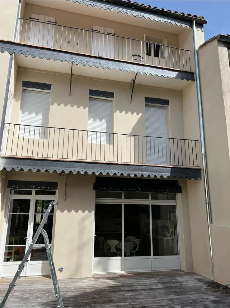 La même maison de ville après ravalement : façade beige uniforme, génoises reprises et balcons remis en état