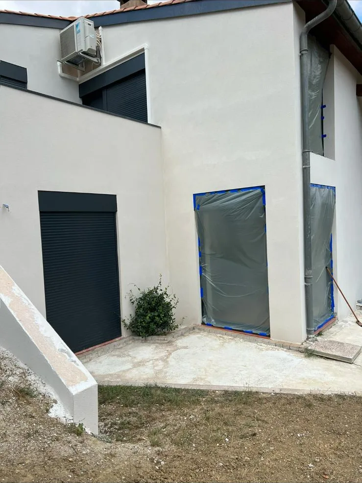 Maison contemporaine à volumes blancs, façades enduites et ouvertures encore protégées en fin de chantier