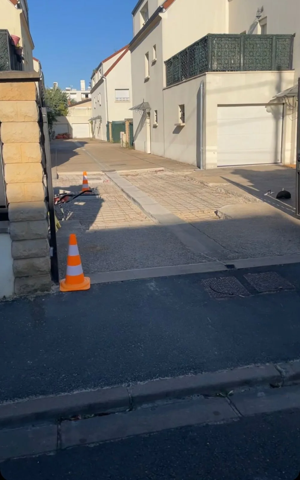 Trottoir et enrobé refaits après passage de réseau, avec regards de visite affleurants