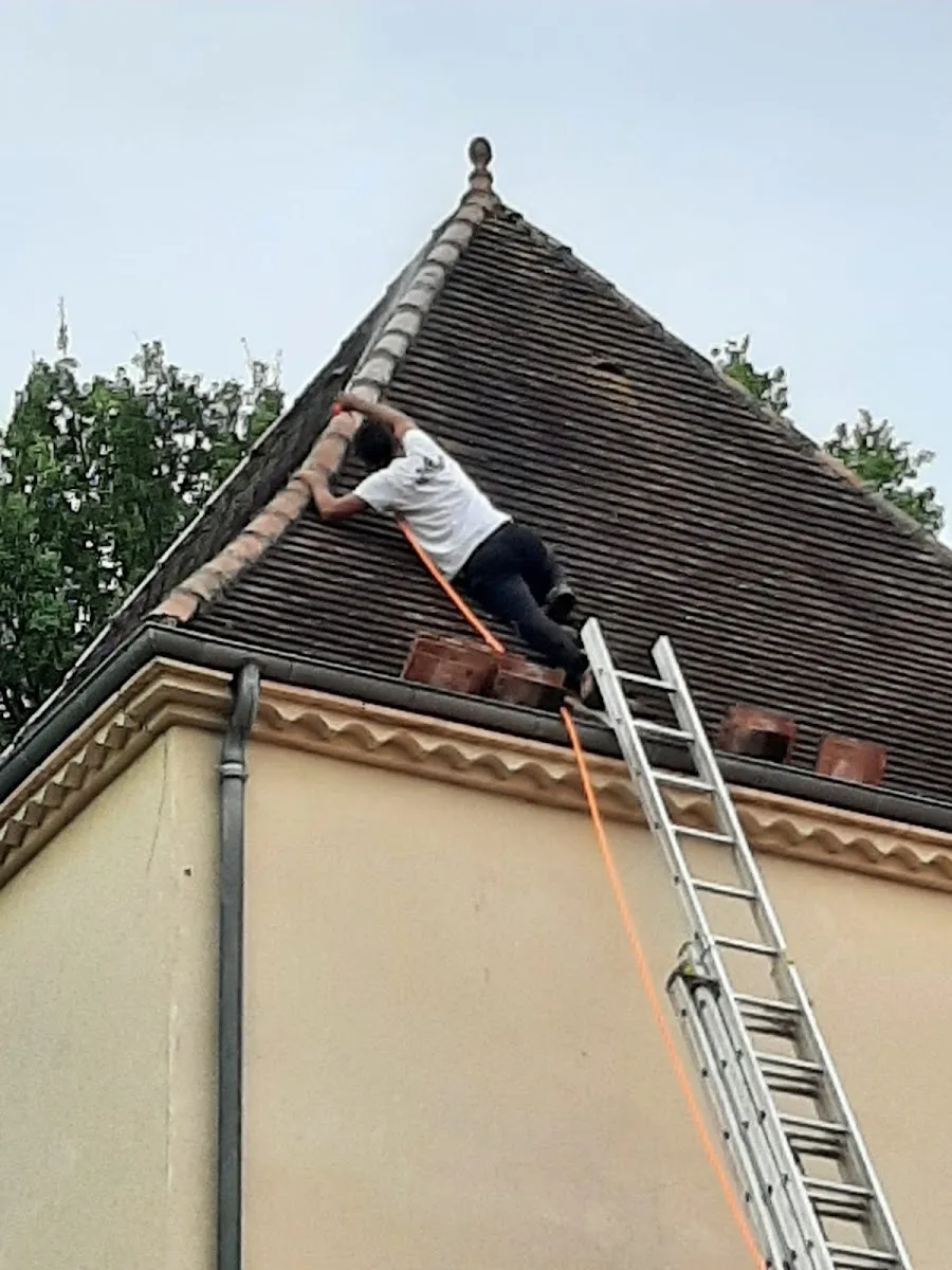 Couvreur en haut d'une échelle intervenant sur le versant d'une toiture