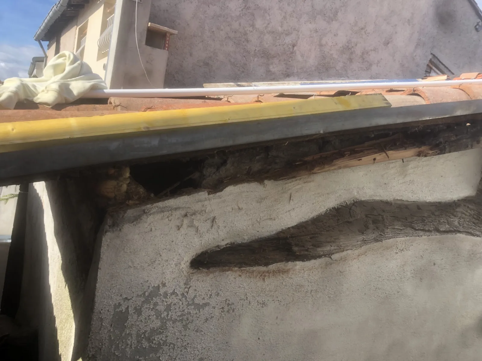 Trace d'infiltration sombre sur un mur sous un chéneau, signe d'une évacuation défaillante